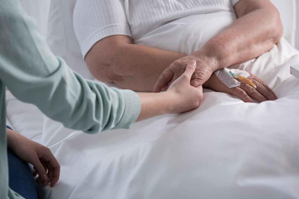 A person in the Boston area on hospice care holding the hand of a Boston Private Nursing In-Home Nurse.