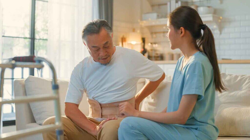 Asian female Physiotherapist instruct advice consulting with senior retired male patient on his body back pain problem,