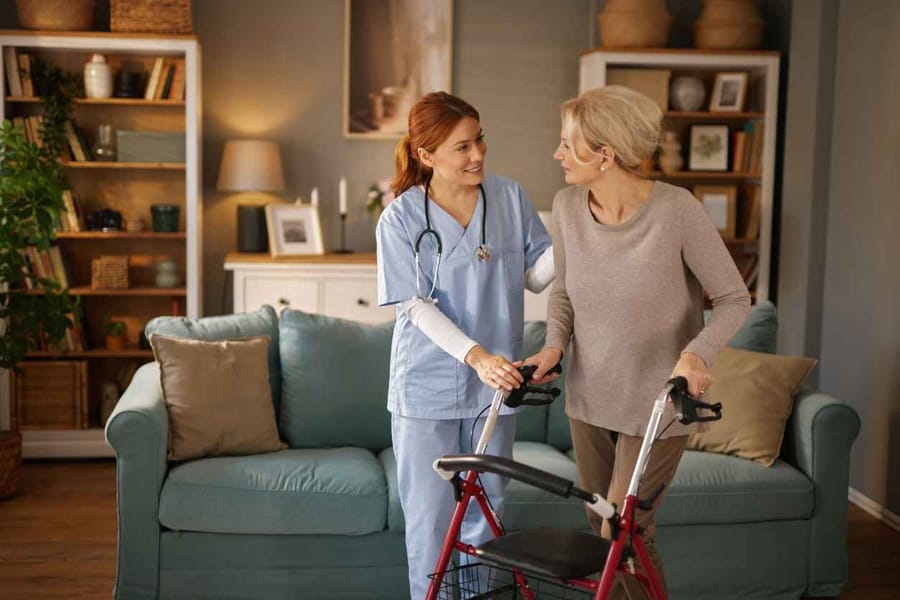 Young nurse assisting a senior woman with her walker in a cozy living room